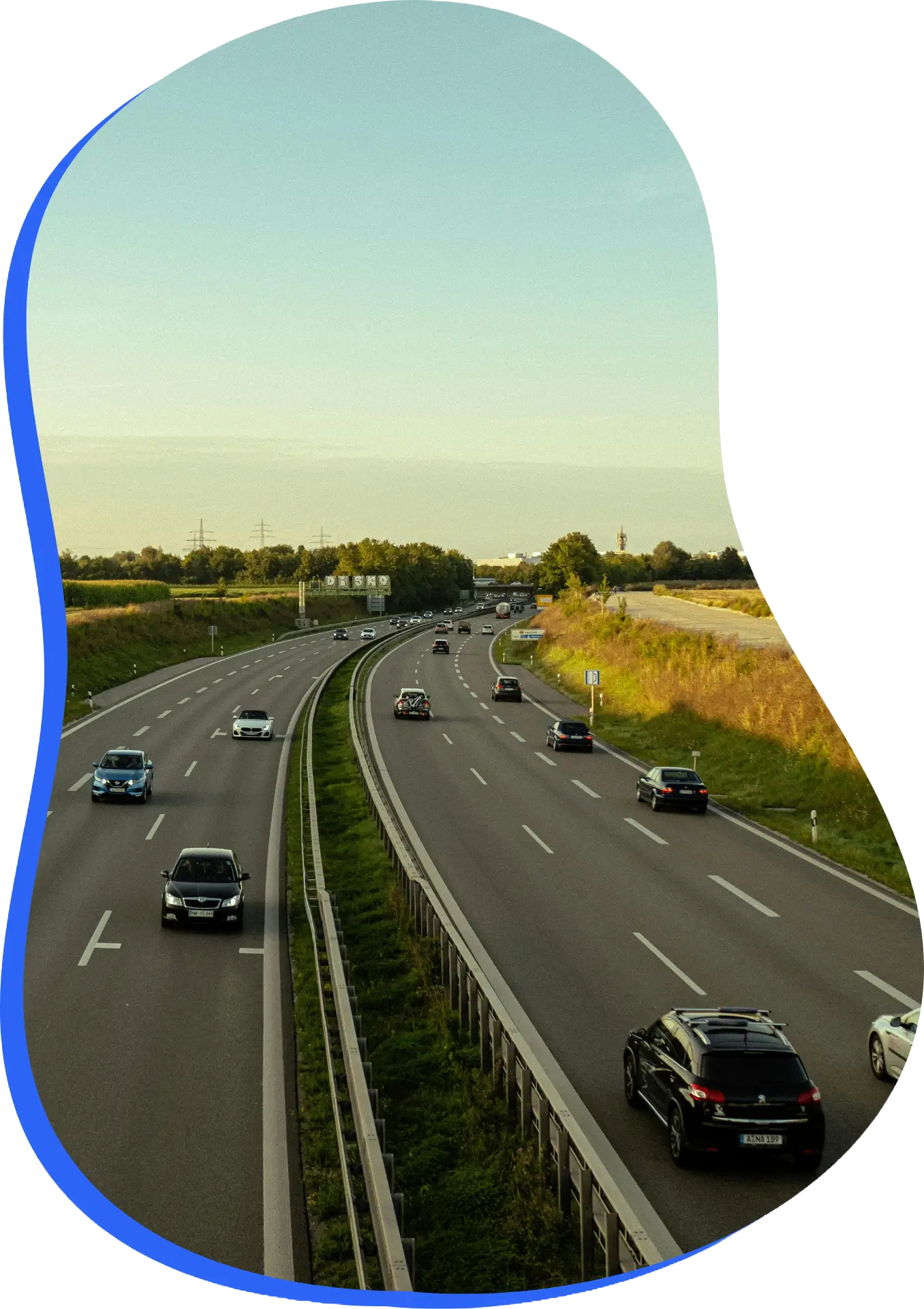 Dálnice s více pruhy, auty v provozu, zelení kolem a modrým zvýrazněním v kruhu.